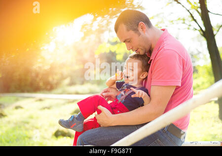 Felice giovane padre con suo figlio in un parco giochi per bambini Foto Stock