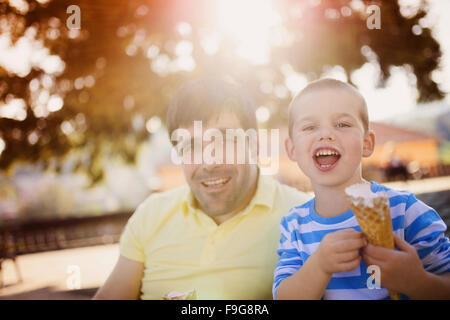 Padre e figlio godendo di gelato al di fuori in un parco Foto Stock