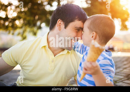 Padre e figlio godendo di gelato al di fuori in un parco Foto Stock