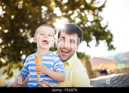 Padre e figlio godendo di gelato al di fuori in un parco Foto Stock