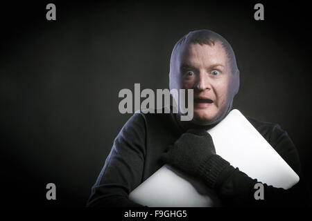 Ladro in azione con passamontagna sul suo volto, vestito di nero. Studio shot su sfondo nero. Foto Stock