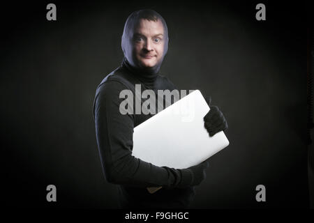 Ladro in azione con passamontagna sul suo volto, vestito di nero. Studio shot su sfondo nero. Foto Stock