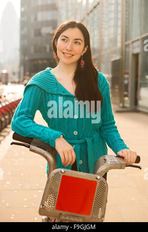 Giovane donna con una bici a noleggio in Londra Foto Stock