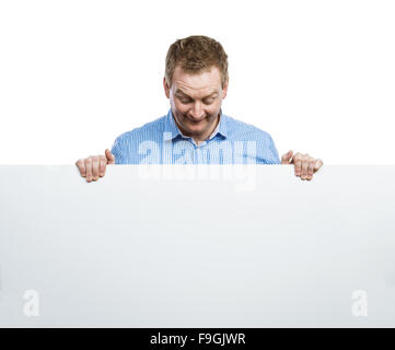 Giovane uomo rendere divertente faccia, tenendo in mano un cartello bianco bordo. Studio shot su sfondo bianco. Foto Stock