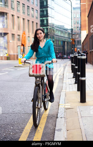 Giovane donna in sella ad una bici a noleggio Foto Stock