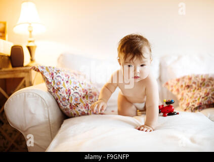 Carino piccolo bambino giocare e divertirsi su un divano Foto Stock