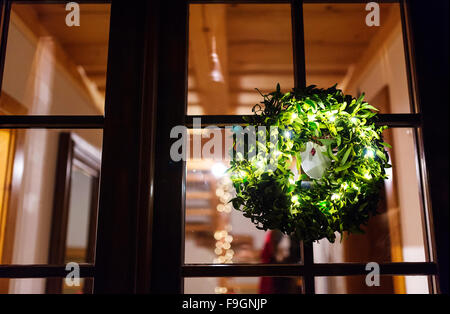 Verde ghirlanda di vischio appeso sulla porta di vetro Foto Stock