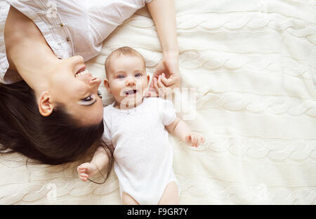 Incantevole piccola bambina e sua madre che giace su una coperta a maglia. Foto Stock