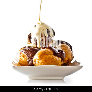 Profiteroles con cioccolata calda e crema sulla piastra bianca Foto Stock