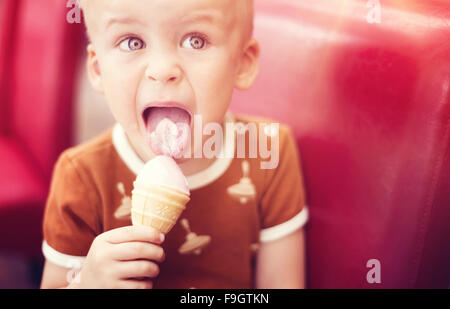 Little Boy godendo il gelato in cafe Foto Stock