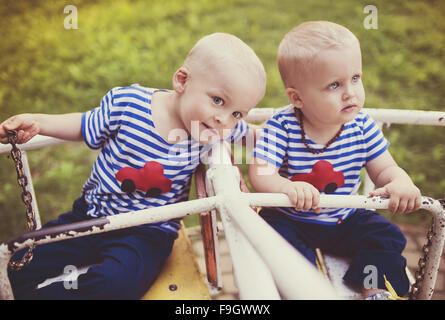 Due simpatici ragazzi piccoli su una vecchia giostra. Foto Stock