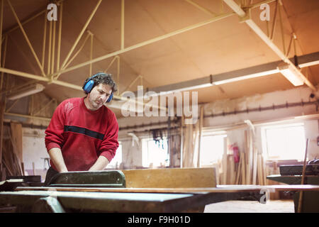 Carpenter il taglio di tavole di legno con sega da tavolo Foto Stock