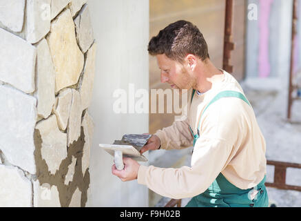 Mason mettendo decorativo pietre naturali su una parete Foto Stock