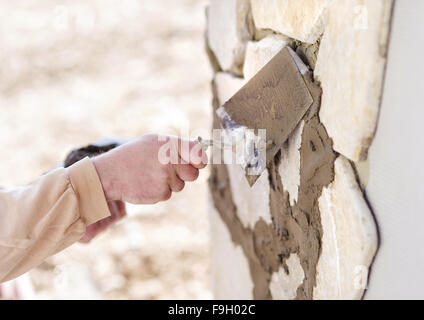 Mason mettendo decorativo pietre naturali su una parete Foto Stock