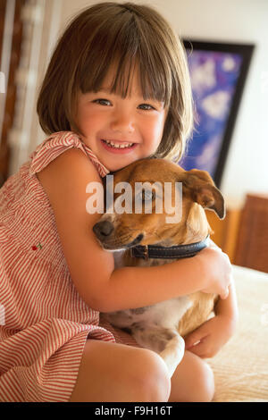 Il Toddler girl abbracciando il suo cane a casa Foto Stock