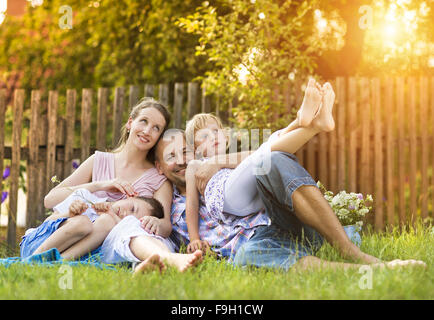 Felice giovane famiglia di trascorrere del tempo insieme al di fuori nel verde della natura. Foto Stock