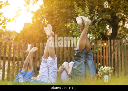 Felice famiglia giovane che mostra le gambe al di fuori nel verde della natura. Foto Stock