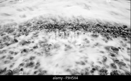 Misterioso in bianco e nero lunga esposizione shot di ciottoli sulla spiaggia tranquilla vicino al mare Foto Stock