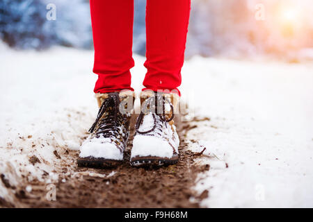 Irriconoscibile woman in red pantaloni e stivali in pelle al di fuori nella neve. Foto Stock