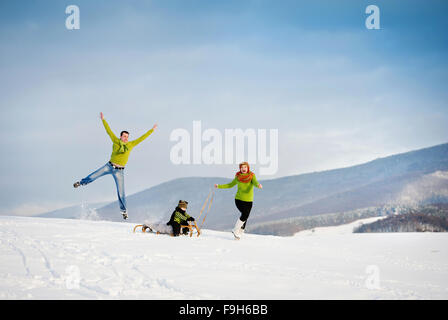 Genitori felici con il loro figlio equitazione sulla slitta avendo divertimento fuori nella neve. Foto Stock