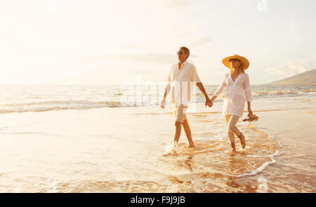 Romantica felice coppia di mezza età godendo bel tramonto a piedi sulla spiaggia. Travel Vacation pensionamento il concetto di stile di vita Foto Stock
