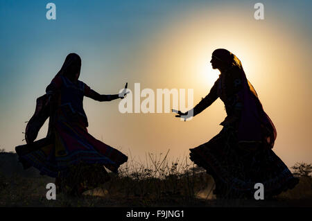 Tramonto, silhouette di due donne zingara ballare una danza tradizionale, Pushkar Camel Fair, Pushkar, Rajasthan, India Foto Stock