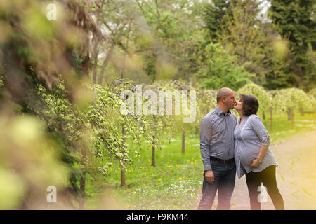 Felice e giovane coppia incinta abbracciando nella natura Foto Stock
