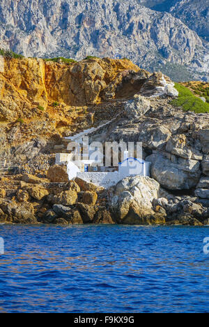 Piccola cappella bianca sotto la scogliera sul mare, Telendos, Kalymnos, Grecia Foto Stock