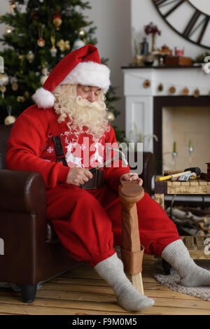 Babbo Natale a casa riparare le sue scarpe, preparazione per il lavoro Foto Stock