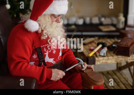 Babbo Natale a casa riparare le sue scarpe, preparazione per il lavoro Foto Stock