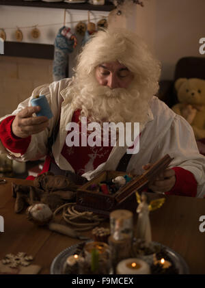 Babbo Natale a lavorare a casa. Riparare i guanti Foto Stock