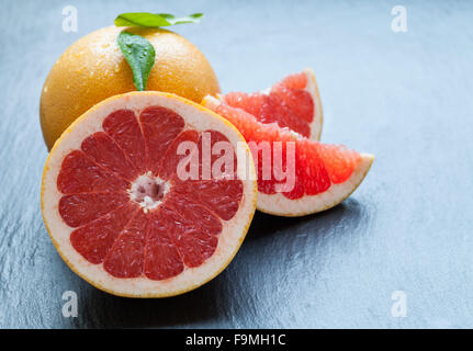 Succo di pompelmo fresco sulla pietra nera Foto Stock