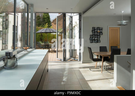 La zona soggiorno a pianta aperta e una cucina con porta a due ante a un ampio patio e le scale che portano al piano seminterrato. Una moderna casa di famiglia. Foto Stock