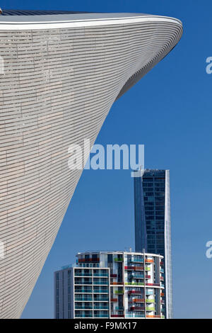 Il tetto curvo del London Aquatics Centre sorge sopra appartamenti residenziali a Stratford, London, E15. Foto Stock