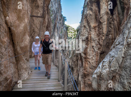 Walkers sul El Caminito del Rey passerella, immobilizzato per le ripide pareti di una stretta gola a El Chorro, Malaga, Andalusia, Spagna Foto Stock