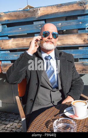 Uomo di mezza etã , bello ed elegante che lavora fuori ufficio in un ambiente rilassato e soleggiata atmosfera Foto Stock