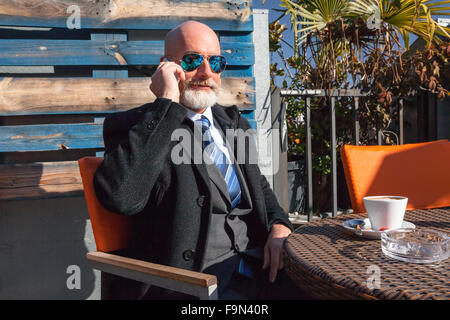 Uomo di mezza etã , bello ed elegante che lavora fuori ufficio in un ambiente rilassato e soleggiata atmosfera Foto Stock