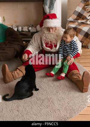 Babbo Natale a giocare a casa con il bambino e il gatto Foto Stock