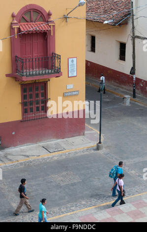 La gente che camminava per strada accanto ad un rosso giallo casa coloniale e angolo a Leon Foto Stock