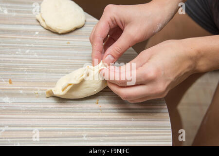 Mani femminili closeup patty stampato con cavolo sul tavolo della cucina Foto Stock