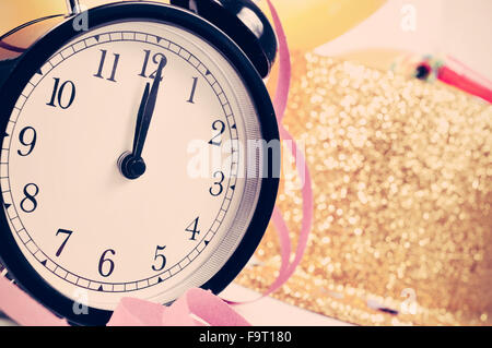 Primo piano di un orologio a dodici, palloncini e un golden top hat, stelle filanti e coriandoli per il nuovo decennio partito, con un effetto di filtro Foto Stock