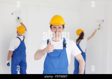 Sorridente giovane costruttore di compressori hardhat che mostra i pollici fino al chiuso Foto Stock