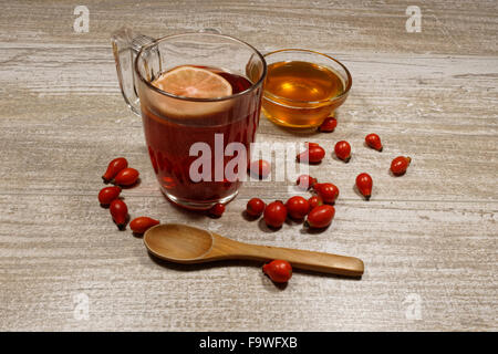 Rosa anca tè con miele e limone sul tavolo di legno Foto Stock