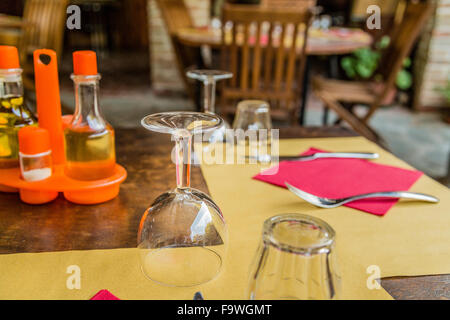 Tavola apparecchiata con olio e aceto bottiglie, sale, forchetta, cucchiaio, tovagliolo di carta e vetro Foto Stock