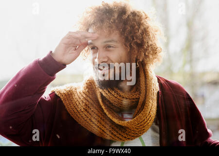 Ritratto di uomo sorridente con tinti boccoli cercando in un vetro di finestra Foto Stock
