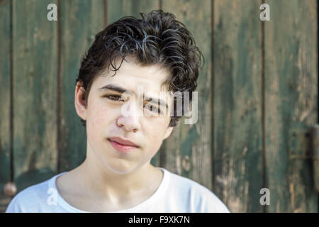 Adolescente con acne scontento davanti un peeling grunge porta in legno Foto Stock