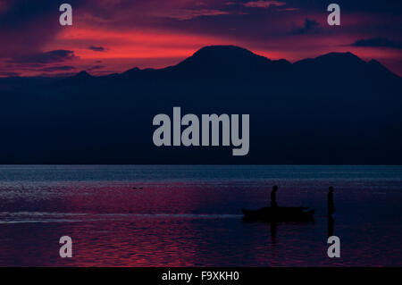 Silhouette di due pescatori in mare al blu purpureo tramonto Foto Stock