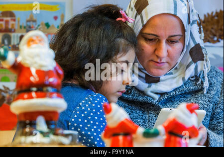 Schwerin, Germania. Xiv Dic, 2015. Cinque-anno-vecchio Nisren dalla Siria e sua madre Abir Kroma partecipare alla festa di Natale per le famiglie di rifugiati e il tedesco vicini nei genitori' cafe del bambino tedesco Tutela League a Schwerin, Germania, 14 dicembre 2015. L'incontro settimanale per le famiglie di rifugiati e residenti di Schwerin appartamento complesso di blocco ha avuto luogo dal mese di ottobre. Oltre a fornire uno spazio per le persone di incontrarsi, il meeting offre anche la possibilità di imparare la lingua tedesca e un luogo per aiutare a chiarire i problemi quotidiani. Foto: Jens BUETTNER/dpa/Alamy Live News Foto Stock