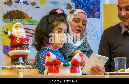 Schwerin, Germania. Xiv Dic, 2015. Cinque-anno-vecchio Nisren dalla Siria e sua madre Abir Kroma partecipare alla festa di Natale per le famiglie di rifugiati e il tedesco vicini nei genitori' cafe del bambino tedesco Tutela League a Schwerin, Germania, 14 dicembre 2015. L'incontro settimanale per le famiglie di rifugiati e residenti di Schwerin appartamento complesso di blocco ha avuto luogo dal mese di ottobre. Oltre a fornire uno spazio per le persone di incontrarsi, il meeting offre anche la possibilità di imparare la lingua tedesca e un luogo per aiutare a chiarire i problemi quotidiani. Foto: Jens BUETTNER/dpa/Alamy Live News Foto Stock