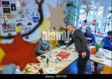 Schwerin, Germania. Xiv Dic, 2015. Rifugiato dalla Siria, Eritrea, Somalia e Iraq partecipare alla festa di Natale per le famiglie di rifugiati e il tedesco vicini nei genitori' cafe del bambino tedesco Tutela League a Schwerin, Germania, 14 dicembre 2015. L'incontro settimanale per le famiglie di rifugiati e residenti di Schwerin appartamento complesso di blocco ha avuto luogo dal mese di ottobre. Oltre a fornire uno spazio per le persone di incontrarsi, il meeting offre anche la possibilità di imparare la lingua tedesca e un luogo per aiutare a chiarire i problemi quotidiani. Foto: Jens BUETTNER/dpa/Alamy Live News Foto Stock